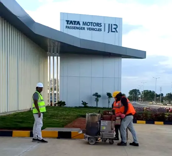 Road marking crew at an automotive manufacturing facility (Tata Motors Passenger Vehicles / JLR signage visible)