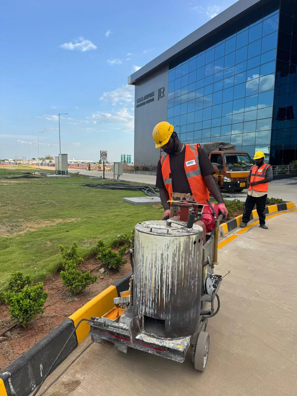 Deepam Road Marking crew with a thermoplastic melting kettle at an automotive facility (Tata Motors Passenger Vehicles / JLR signage visible)